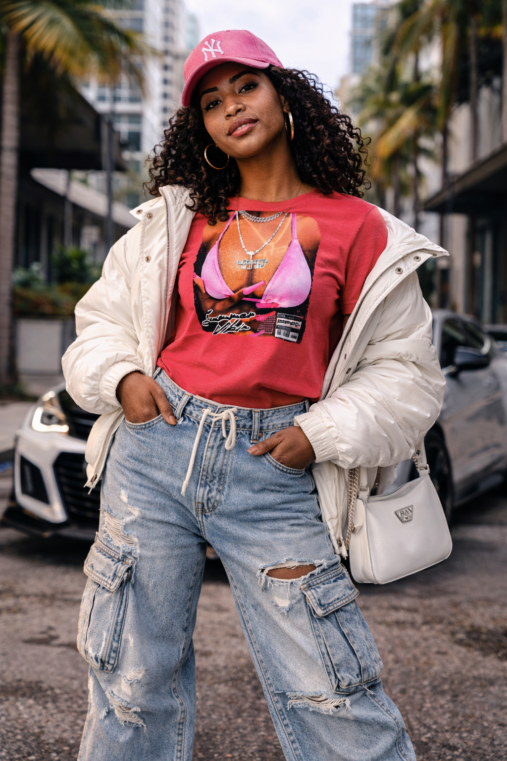 Person wearing a red graphic t-shirt, white jacket, and blue jeans in an urban setting.