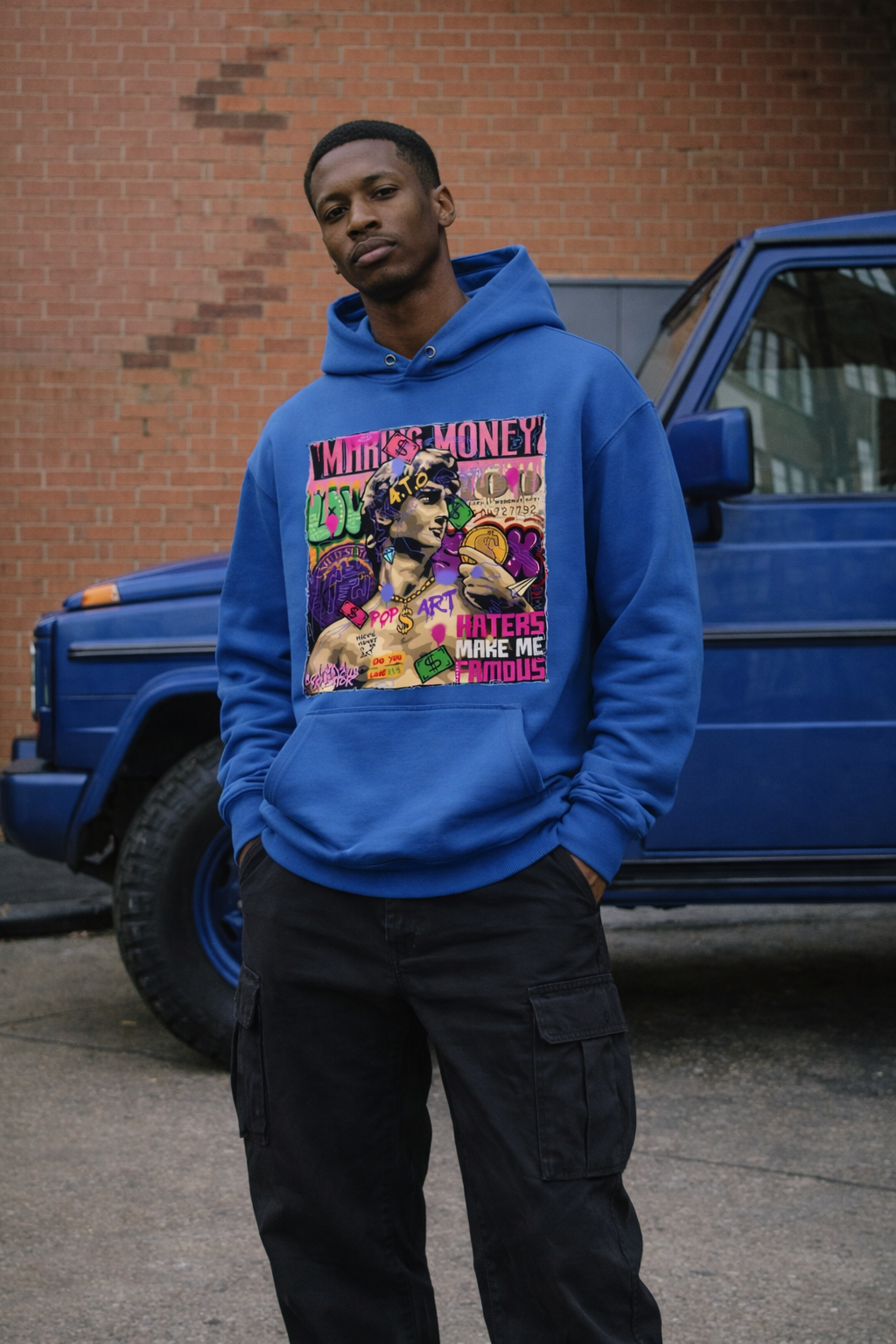 Person wearing a blue hoodie with a colorful graphic design in front of a blue truck.